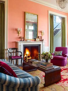 a living room filled with furniture and a fire place under a chandelier in front of a window