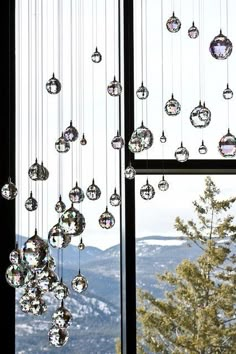 a window with some ornaments hanging from it's side and mountains in the background