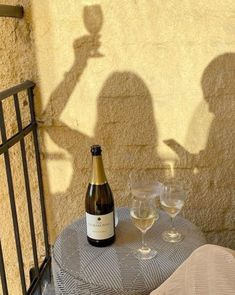 a bottle of wine sitting on top of a table next to two glasses of wine