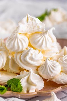 a plate topped with whipped cream on top of a white table cloth next to green leaves