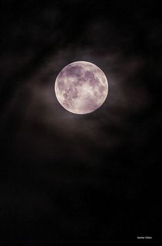 the full moon is seen in the dark night sky with some clouds around it,