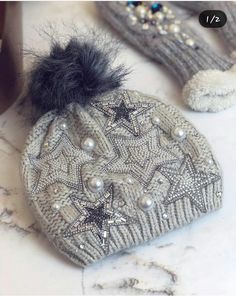 two knitted mittens with stars and pearls on them, one has a pom - pom