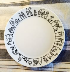 a white plate with black designs on it sitting on a striped tablecloth covered surface