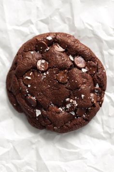 a close up of a chocolate cookie on a piece of paper with crumbs