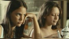 two young women sitting at a table with a teapot in the foreground and one on the right