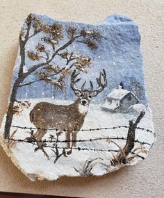 a rock with a painting of a deer on it's side next to a fence