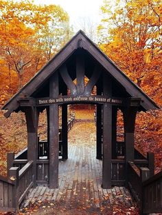 a wooden gazebo surrounded by trees in the fall