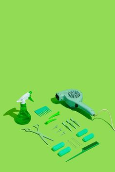 a hairdryer, combs, scissors and other items on a green background