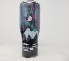 a glass vase with trees and the moon in the sky painted on it's side