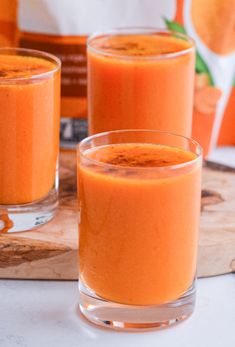 two glasses filled with orange juice on top of a table