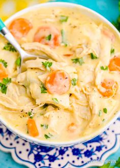 a close up of a bowl of chicken noodle soup on a blue and white plate