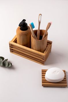 a wooden holder with toothbrushes, soap and brush in it on a white surface