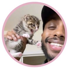 a man holding a kitten up to his face in front of a pink circle frame