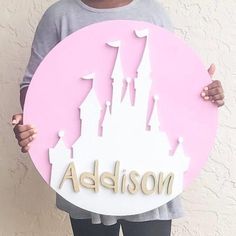 a person holding up a sign that says madison in front of a castle with the word disney written on it