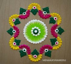 a colorful rangolite with flowers and leaves in the center on a wooden surface