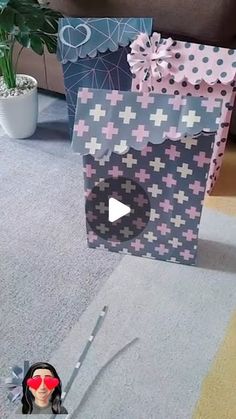 a small doll is sitting on the floor in front of some shopping bags that are decorated with pink and blue crosses