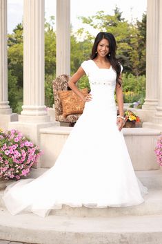 a woman in a white wedding dress posing for a photo on some steps with flowers