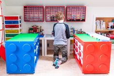 a young boy standing in the middle of a room with legos on the walls