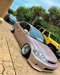 two cars parked next to each other on the side of a road with palm trees in the background