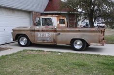 an old truck is parked in front of a house with a garage door on the side