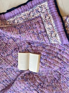 an open book laying on top of a purple quilt