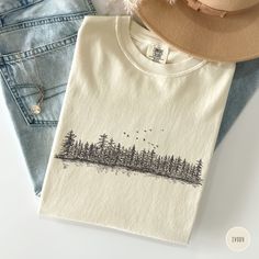 Embrace your adventurous spirit with this Comfort Colors t-shirt featuring a graphic of pine trees. Perfect for nature lovers and granola girls, this wilderness-inspired shirt is an ideal gift for campers, hikers, and those who love to explore and enjoy bonfires. Prefer this design on a Sweatshirt? Visit this link: https://bohemianbloomdesigns.etsy.com/listing/1756263663 👕 T-Shirt Brand Comfort Colors 1717 | Unisex Adult Sizing | 100% Ring-Spun US Cotton ⏳🚚 Production & Shipping All items are Granola Graphic Tees, Cotton Graphic Print Tops For Outdoor Activities, Cotton Graphic Tee For Outdoor, Long Sleeve Graphic Tee For Outdoor, Cotton Screen Print Tops For Outdoor Activities, Graphic Print Cotton Top For Outdoor Activities, Relaxed Fit Cotton Tops For Adventure, Short Sleeve Printed Tops For Outdoor, Printed Short Sleeve Tops For Outdoor