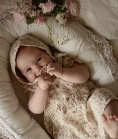 a baby is laying down in a crib with flowers on the bed behind it