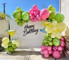 a happy birthday sign made out of balloons and limes on the side of a building