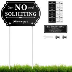 a no soliciting sign sitting on top of a green grass covered field next to a street sign