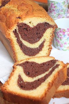 a close up of a sliced cake on a plate with a cup in the background