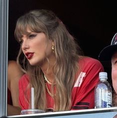 two people sitting in the stands at a baseball game, one wearing a red shirt