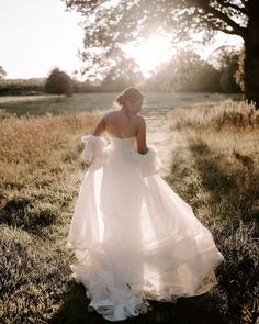 a woman in a white dress is walking through the grass