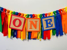 a colorful banner with the word one hanging from it's side on a white wall