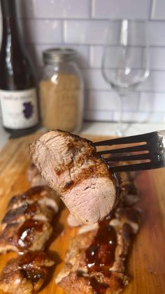 a piece of meat on a wooden cutting board with a knife and fork in it