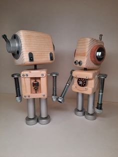 two wooden toy robots are standing next to each other with screws in their hands