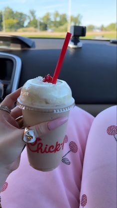 a person holding a drink in their hand while sitting in the back seat of a car