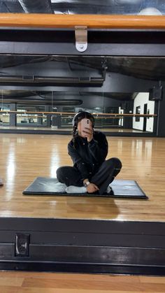 a woman sitting on top of a wooden floor in front of a black suitcase with her face painted