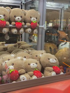 teddy bears and other stuffed animals are on display in a store window with red strawberries