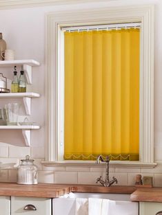 a kitchen with white cabinets and yellow curtains on the window sill above the sink