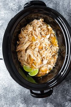 shredded chicken in a slow cooker with limes on the side