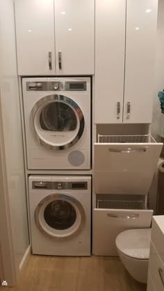 a washer and dryer in a small room with white cabinets on the walls