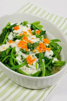 a white bowl filled with green beans and carrots on top of a striped table cloth