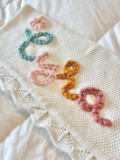 the crocheted scarf is laying on top of the white bed sheet with colorful rings