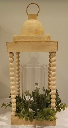 a wooden lantern with plants in it on a table