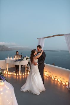 a bride and groom share their first dance on the deck of an oceanfront wedding venue