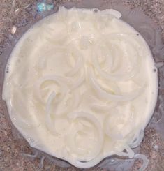 a bowl filled with white liquid on top of a counter next to a marble surface