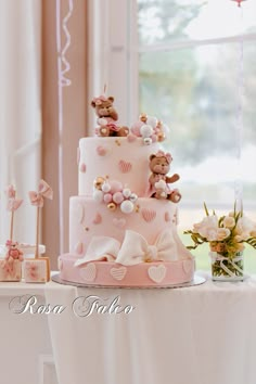 a three tiered pink cake with teddy bears on top and balloons in the background