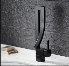 a black faucet sitting on top of a sink next to a gray wall