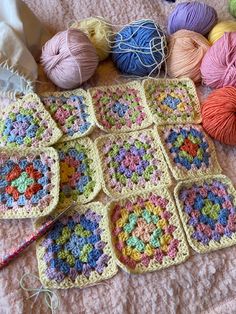 crocheted squares and balls of yarn laid out on a bed