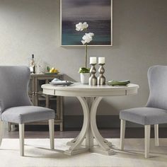 a white table with two chairs and a vase on it